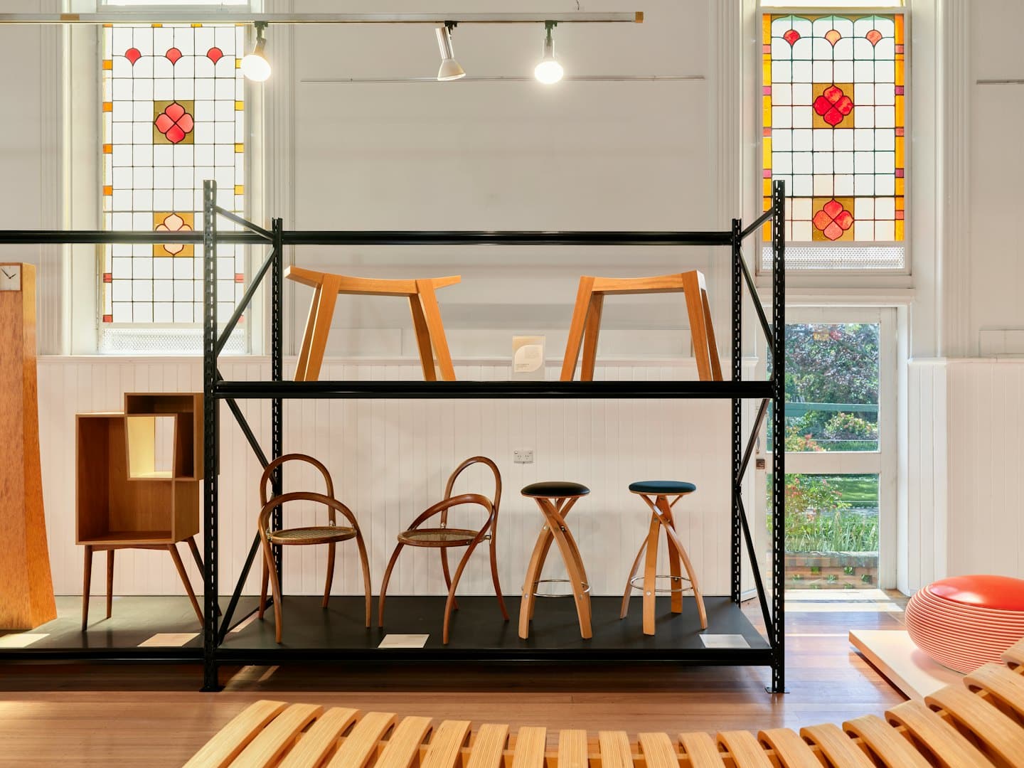 Arredamento moderno in legno disposto su scaffalature industriali in uno showroom.