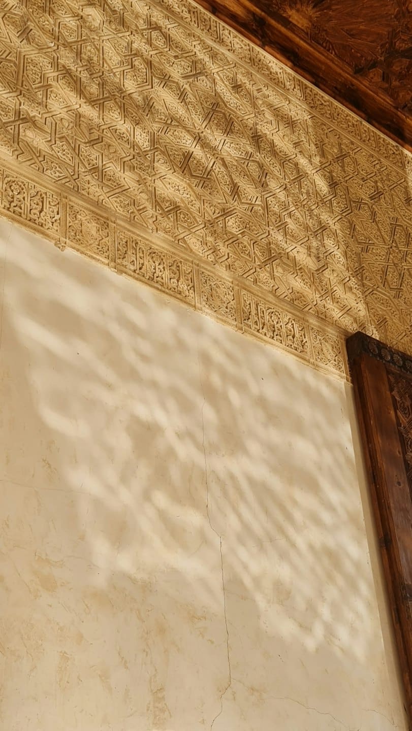 Intricati intagli geometrici decorano un soffitto e una parete storici ornati.